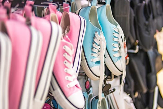 many sports sneakers with pink and blue fabric hanging in the store. High quality photo