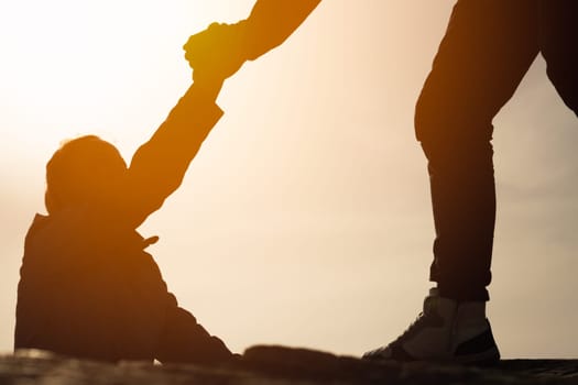 Giving a helping hand. Man helping female climber up a mountain.silhouette of a man gives a hand to a girl on a mountain, the concept of mutual assistance, place for an inscription. High quality photo