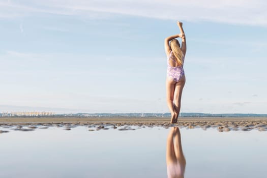 in a swimsuit image of a full length teenager girl posing from behind, enjoying the amazing ocean view, spinning and having fun, relaxing in freedom. High quality photo