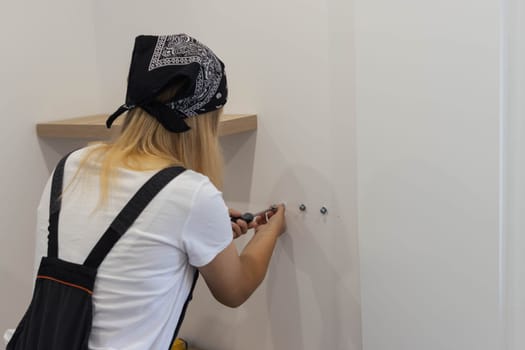 the girl spins the shelf for books on the wall. the girl, blond hair and a black bandana on her head, gender equality. On the right there is a place for an inscription. High quality photo