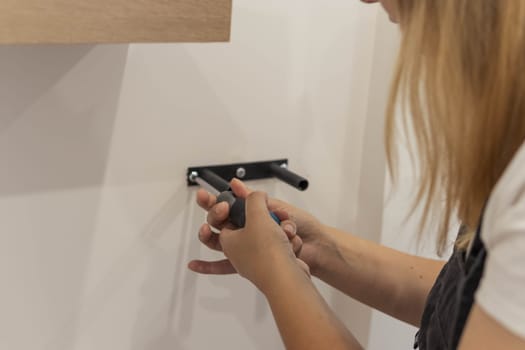 the girl spins the shelf for books on the wall. the girl is turned back to the camera close-up, blond hair and a black bandana on her head. High quality photo