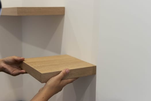 the girl is doing men's work,gender equality.the girl is screwing a shelf for books at home.close-up of the hand there is a place for the inscription. High quality photo