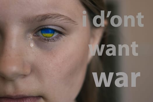 ukrainian baby girl cryingn on the right is the inscription I don't want war in white letters.Ukraine flag in the pupil of a child yellow blue color.Stop the war in ukraine. High quality photo