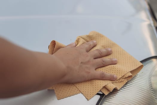 The girl wipes the window in the car with a yellow special cloth for windows.Close-up of a hand and a rag.there is a place for an inscription. The concept of work and cleanliness. High quality photo