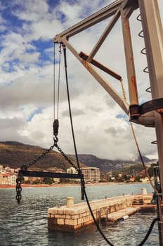 metal crane over the water in the sea in the background sea and mountains view. High quality photo