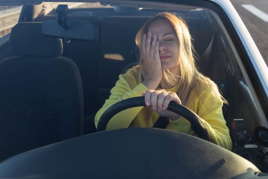 tense or tired girl in the car sits at the helm, the car broke down on the road. High quality photo