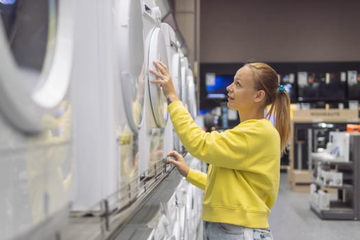 a woman of European appearance with blond hair tied in a ponytail in a yellow sweater, looks at a washing machine in a store. Close-up of her face The concept of home cleanliness. High quality photo