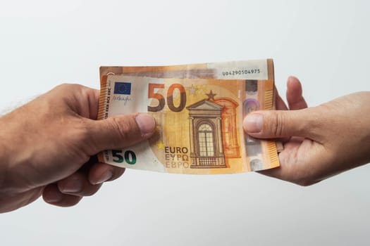 hands men and girl giving money 50 euro isolated on white background close-up.Finance concept.male hand gives 50 euro to female hands on a white background. High quality photo