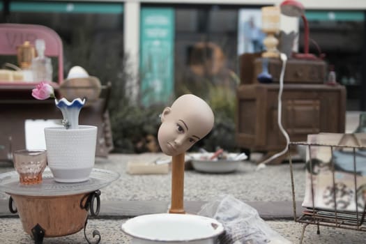 antique and old things are sold at the fair. The head of the doll is on the rack, a lot of different things. there is a place for an inscription on the side.Fair in the French city. High quality photo