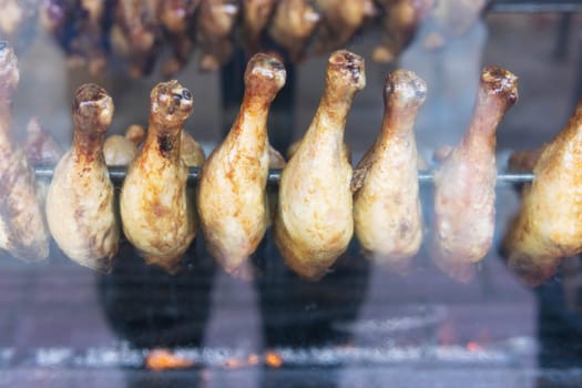 chicken legs are fried in a shop window for sale to hungry people, smoke a grill. High quality photo