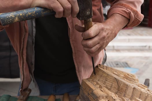 a man makes products from a tree with his own hands and with a tool close-up of a hand a tree. High quality photo