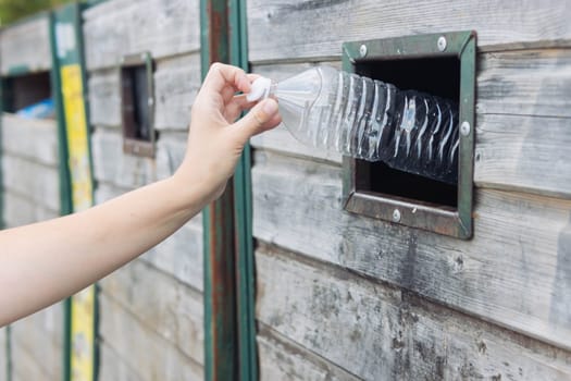 a girl throws a plastic bottle into special bins for plastic waste.Close-up of a hand isolated near the bins with garbage.The concept of cleanliness in the surrounding world. High quality photo