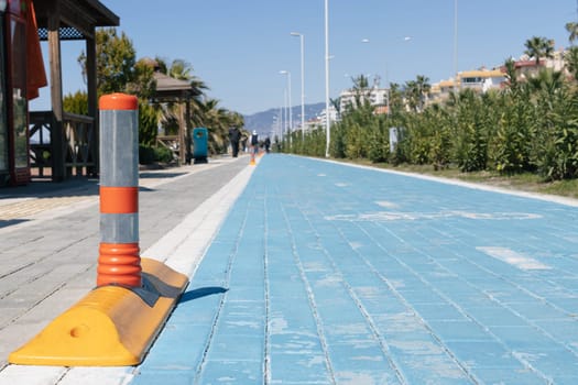 Blue cycle path and pedestrian path, close-up view from below. Around green trees and palm trees. High quality photo