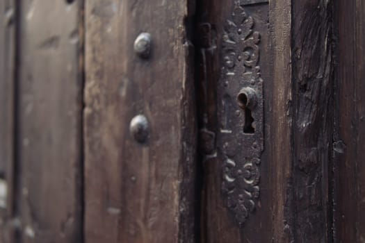 brown wooden antique door with a metal lock close-up, there is a place for an inscription. High quality photo