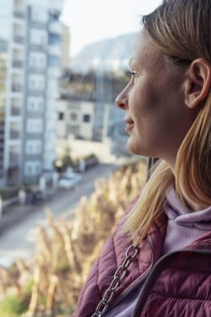 girl of European appearance with blond hair standing looking at buildings side view portrait. High quality photo