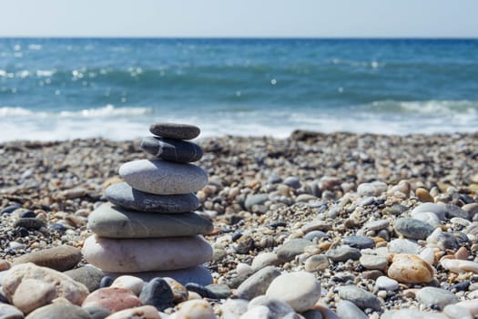 Pyramid of sea pebbles on a sunny sandy beach. The concept of life balance and harmony on the right there is a place for an inscription. High quality photo