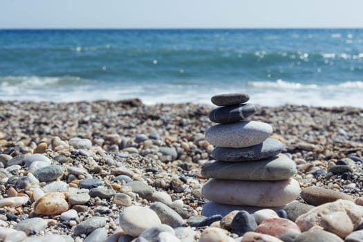 Pyramid of sea pebbles on a sunny sandy beach. The concept of life balance and harmony on the left there is a place for an inscription. High quality photo