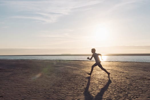 a boy runs on the beach at sunset, a silhouette of a child running on the beach on the sand near the water, there is a place for an inscription. High quality photo