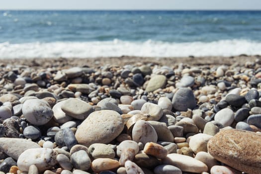 a beach with dark and light pebbles, blue sea and sky, there is a background and a place for an inscription. High quality photo