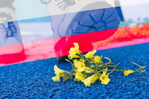 a man with a shoes steps on yellow flowers on a blue background.Flag of Russia.there is a place for the inscription.Aggressor,war in Ukraine stop. High quality photo