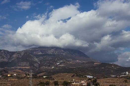 View of a beautiful mountain and sky with space for text, small houses at the bottom background. High quality photo