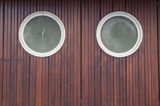 small round two windows in brown doors, brown background texture with a place for an inscription. High quality photo