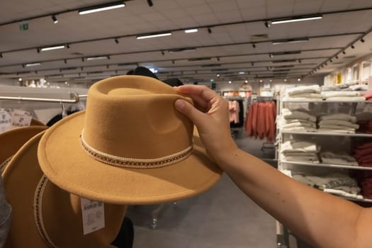 a close-up female hand holds a brown hat in a store. A girl chooses a hat for autumn. There is a place for an inscription. High quality photo