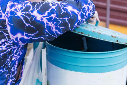 girl throws garbage into a metal trash can with a lid. High quality photo