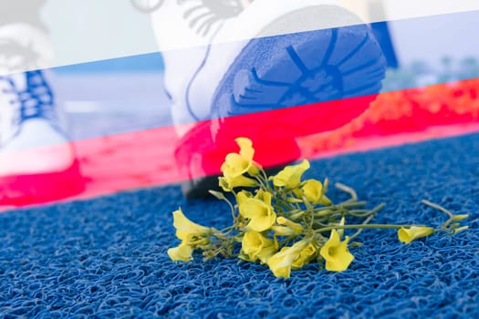 a man with a shoes steps on yellow flowers on a blue background.Flag of Russia.there is a place for the inscription.Aggressor,war in Ukraine stop. High quality photo