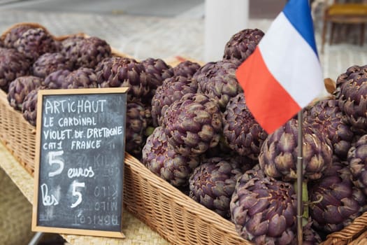 Artichokes are sold on the showcase, healthy food. Photo angle from the side. Artichokes are sold on the French market, the price of an artichoke is written on the side. High quality photo
