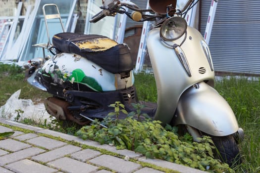 a broken moped stands in the open air on the street in the grass. High quality photo