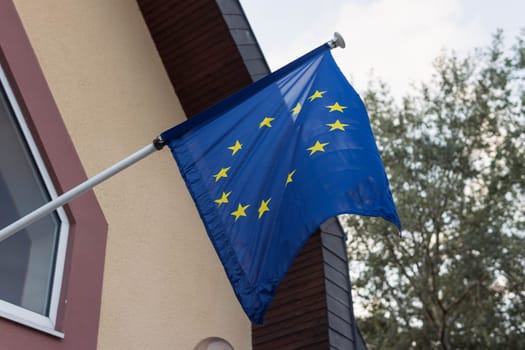 Flying EU flag on the building wall EU flag fluttering in the wind close-up. High quality photo