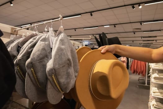 a close-up female hand holds a brown hat in a store. A girl chooses a hat for autumn. There is a place for an inscription. High quality photo