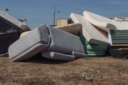 Dirty used mattresses and a sofa are dumped in a landfill. High quality photo close up