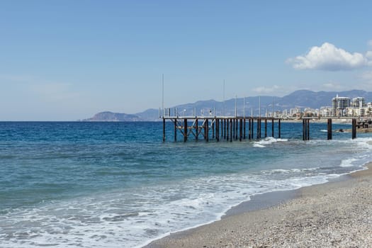 wooden pier on the sea or river with a view of a beautiful mountain and the city in a summer early morning side view. High quality photo