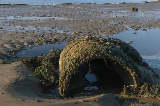 Old concrete circular pipe on the beach near port. Big abandoned concrete tube made for construction of sewerage system.High quality photo. High quality photo