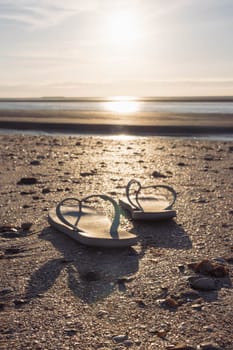 a pair of flip flops isolated on the background of the sky, ocean and sand on the beach at sunset. Beautiful landscape, on the right there is a place for an inscription. High quality photo