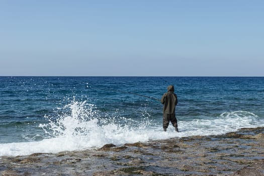 a man fishes in the sea or river in a rubber suit with a fishing rod in his hands. High quality photo