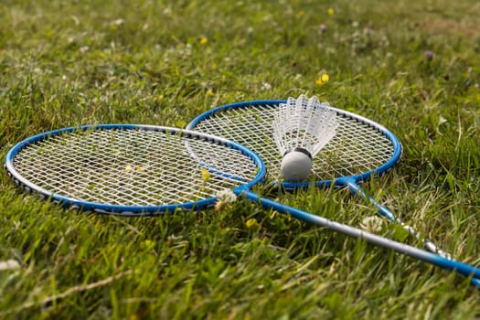 Shuttlecock and badminton rackets on green grass. High quality photo