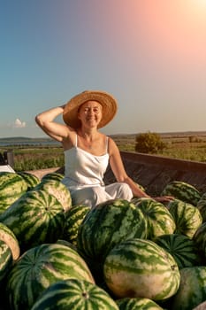 watermelon woman. He sits in a hat on a mountain of watermelons. Trailer with watermelons in the market