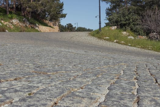 the road from the pavement is old in the city. There are green trees around, there is a place for an inscription. High quality photo