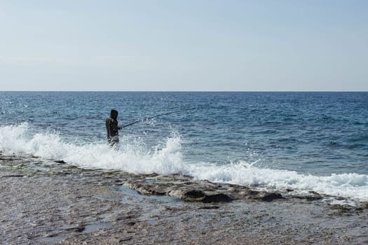 A man is fishing with fly fishing in the morning river or sea, strong waves. High quality photo