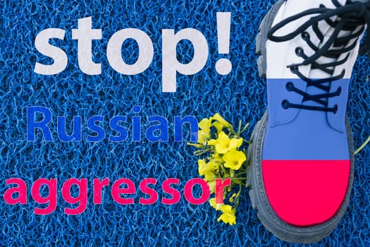 boot the flag of Russia steps on yellow flowers on a blue background.Flag of Ukraine.Left inscription stop Russia aggressor, war in Ukraine. High quality photo