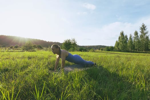 a girl of European appearance, goes in for sports outdoors at sunset in the park. The girl is dressed in a blue suit for fitness. The concept of sports and a healthy lifestyle. High quality photo