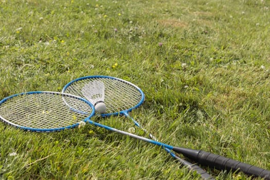 Shuttlecock and badminton rackets on green grass. High quality photo