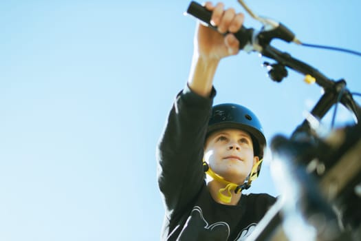 portrait of a teenager boy against the blue sky, a child on a bicycle in a black helmet to protect his head. there is a place for an inscription. High quality photo