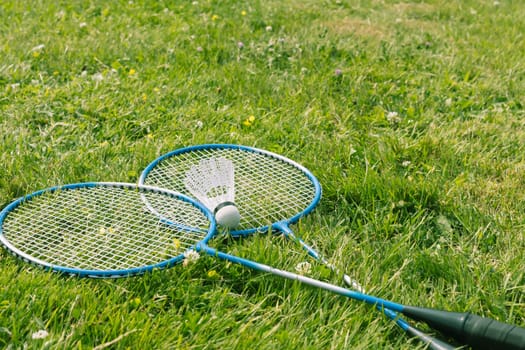 Badminton - shuttlecock on rackets on badminton courts on green grass. High quality photo