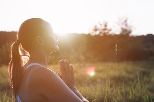 silhouette of a girl of European appearance at sunset, a round plan on the face, there is a place for an inscription on the side, the girl is doing yoga. High quality photo