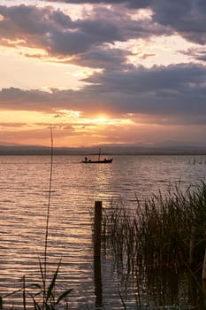 A sunset over the Valencia lagoon amidst the clouds.Reeds, reflections, calm waters, Mediterranean tradition and ecosystem,