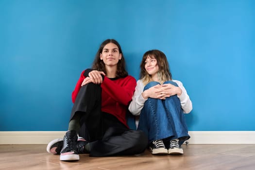 Portrait of a teenage couple of young students on a blue background. Youth, color, lifestyle, friendship, young people concept